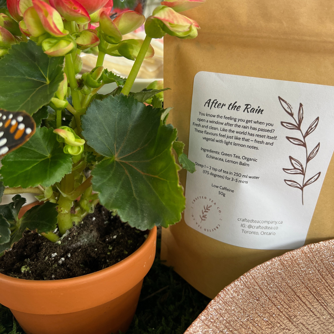 Tea package labeled 'After the Rain' next to a potted plant with a butterfly.