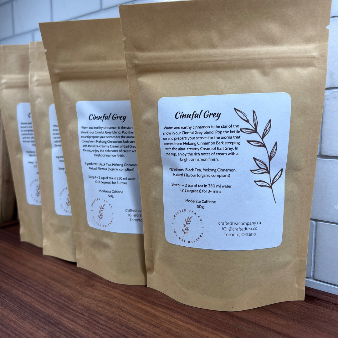 Four packages of Cinnful Grey loose leaf tea on a wooden tray