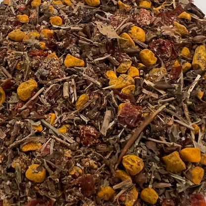 Close-up of a mix of dried herbs and spices with yellow and red elements that are turmeric, rosehips and strawberries