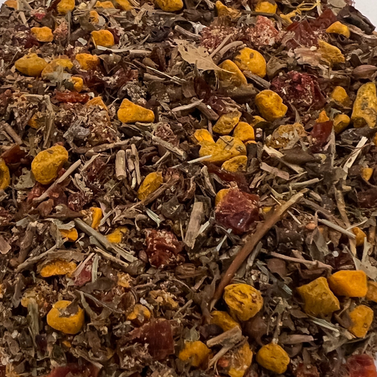 Close-up of a mix of dried herbs and spices with yellow and red elements that are turmeric, rosehips and strawberries
